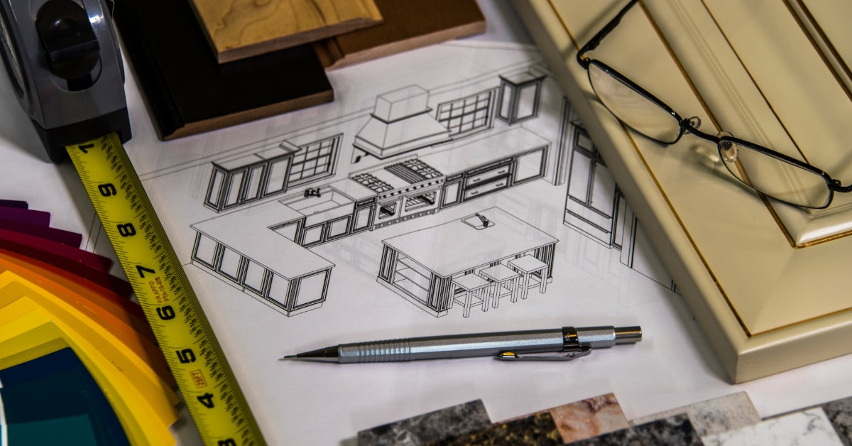 A kitchen remodeling blueprint sitting on a table. The blueprint is partially covered by a pen and building materials.